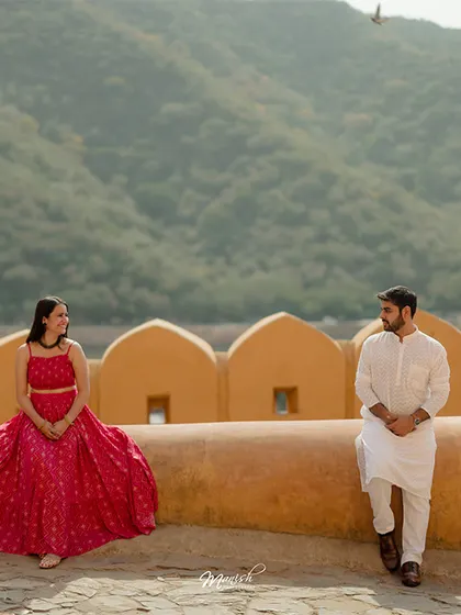 A beautifully composed shot on the fort walls, with the Aravalli hills in the background, showcasing the grandeur of a Jaipur pre-wedding shoot.