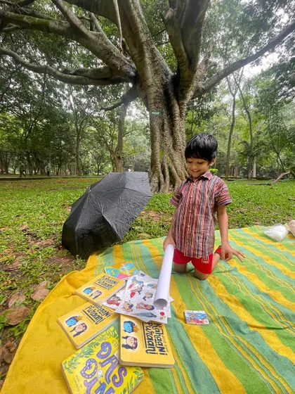 A young boy proudly kneels over his collection of books and sticker sheets. Providing materials for creative expression is a key part of our workshop philosophy.