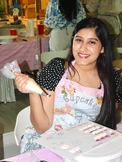 A happy guest proudly holding her piping bag, ready to create some beautiful designs at our workshop.