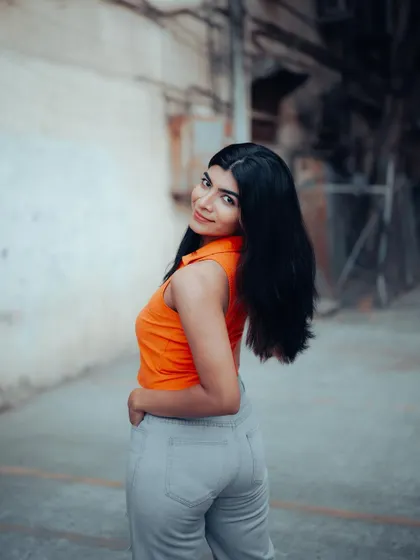 A candid-style portrait of a model in an urban alley. Her natural movement and the gritty background create an authentic and cool shot.