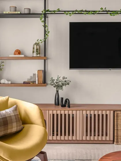 A detail of the living area, showcasing the custom wooden TV console with slatted details and a woven basket for storage. The open shelving provides a space for personal decor, adding to the room's warm and lived-in feel.
