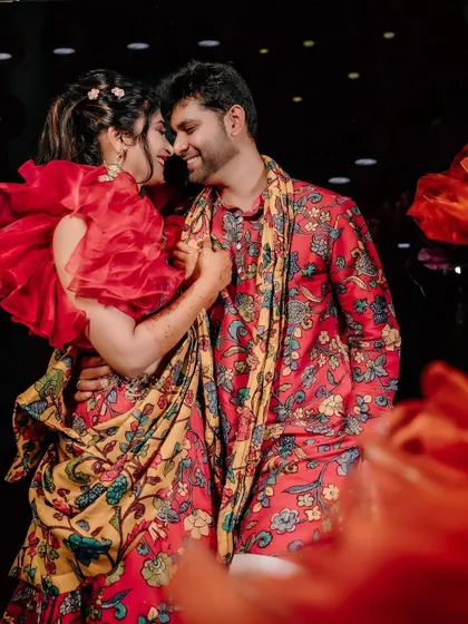 A quiet moment between the couple amidst the celebration. The rich textures and colours of the Mehendi decor, from the floral arrangements to the patterned textiles, create a warm and intimate setting.