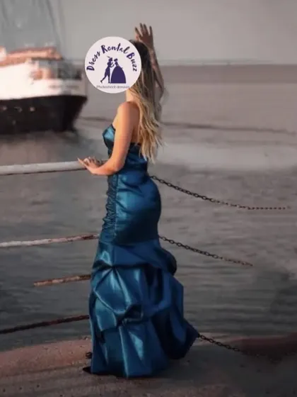 A client wearing our teal blue satin gown for a photoshoot by the water.