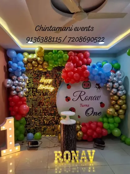 A first birthday backdrop for Ronav combines colourful balloons, a personalised round panel and illuminated name and age lights.