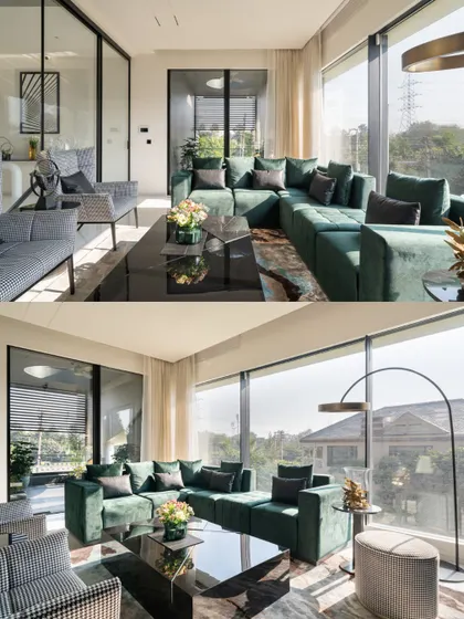 The living area in Residence 100 features a bold emerald green sectional sofa, adding a vibrant pop of color against the neutral palette and large glass windows.