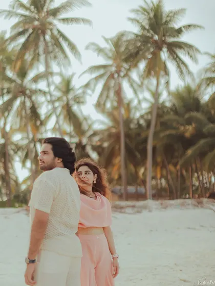 A candid shot capturing a natural, unposed moment between the couple as they enjoy the beach, with palm trees framing the scene.
