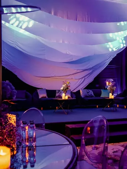 A lounge area at the cosmic-themed sangeet, with deep blue lighting and flowing drapes creating a moody, celestial vibe.