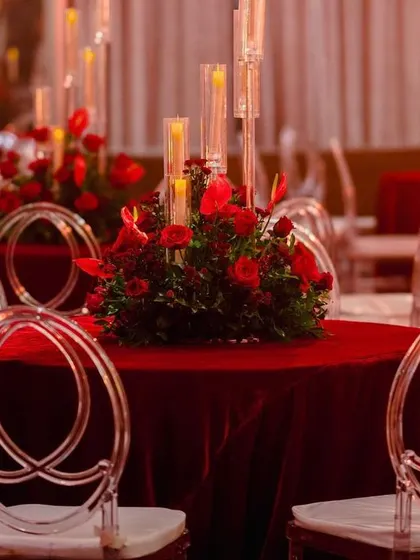 A luxurious centerpiece featuring a bouquet of deep red roses in a golden vase. This classic and elegant detail was part of a glamorous red-themed reception.