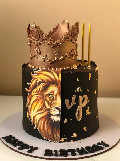 A royal-themed cake in black and gold, featuring a lion's face and an ornate crown topper.