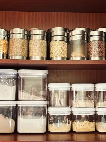 Decanting pantry items like dals, grains, and flours into clear, uniform containers creates a clean, organized look and helps you see your stock at a glance.