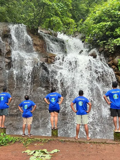 Our team, wearing the Trekker's Adda T-shirt, posing in front of a waterfall. We are a community of adventurers.