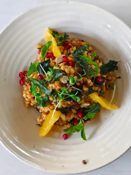 A refreshing pearl barley salad with orange segments, pomegranate seeds, and fresh mint.