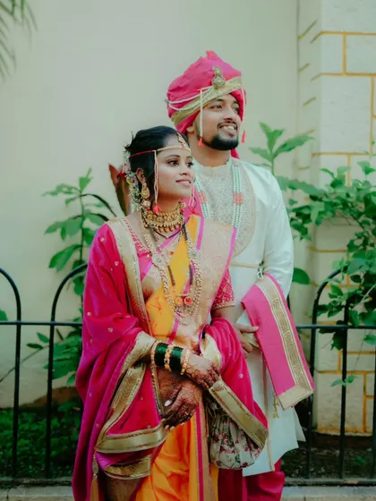 A classic portrait of the couple standing together, holding hands against a backdrop of lush greenery.