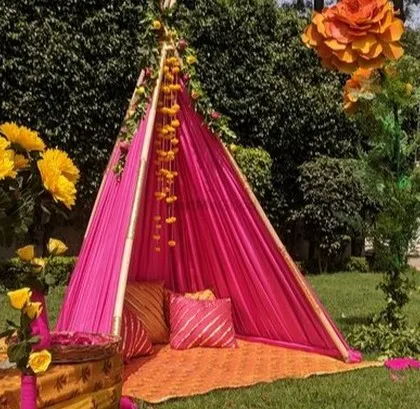 A cozy and colorful Mehendi seating area with a teepee-style tent in bright pink.