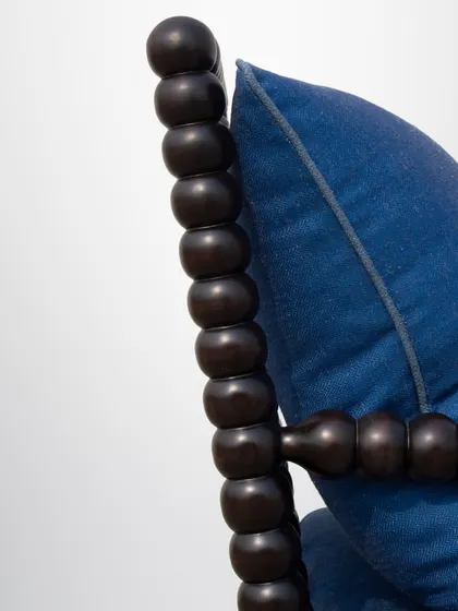 A close-up of the turned wood detail on the armchair's frame, a testament to the skill of our craftsmen.