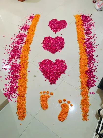 A beautiful flower petal rangoli I created for a baby girl's welcome. The design features hearts and tiny footprints made from pink rose and orange marigold petals.