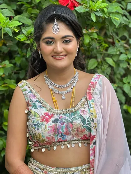 A smiling portrait of Ashitha. The minimalistic makeup enhances her natural beauty and is perfect for an outdoor, daytime celebration.
