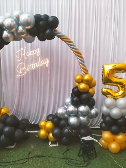 An elegant black, gold, and silver balloon arch for a 50th birthday, complete with large foil numbers and a 'Happy Birthday' sign.