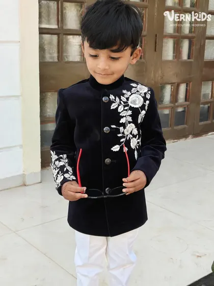 A full-length shot of our client looking dapper in the black velvet Indo-western jacket. Paired with white pants, it creates a striking, high-contrast look perfect for a wedding baraat.