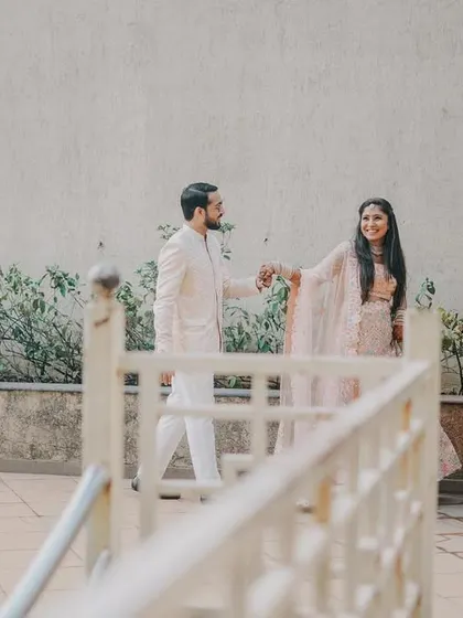 A wider perspective of the couple during their engagement shoot, using architectural elements like the railing to frame the scene.