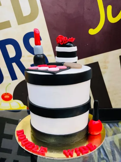 A 1.5kg makeup theme cake with a black and white striped design and fondant cosmetics.