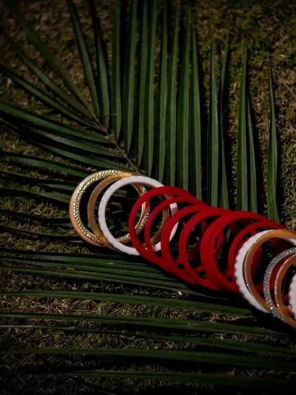 A creative flat-lay of the bride's traditional red and white wedding bangles. We take artistic shots of your important wedding accessories.