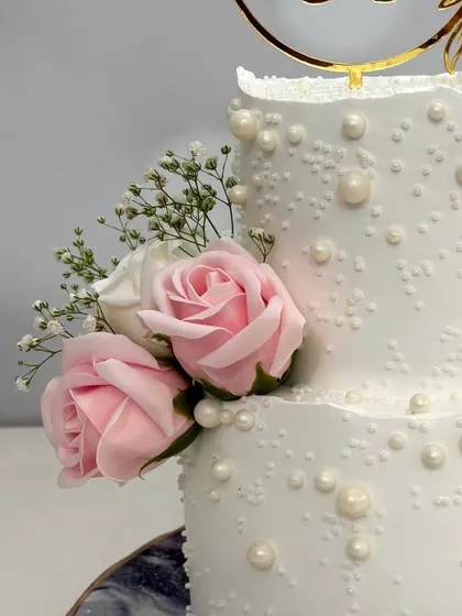 A close-up of the delicate pink roses and edible pearls on this two-tier engagement cake. It’s these small, handcrafted details that make each cake truly special.