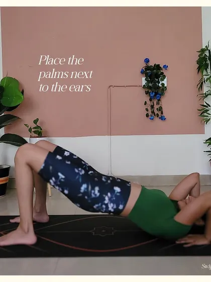 Step 3 for Upward Bow Pose: Place the palms on the floor next to your ears, fingers pointing towards your shoulders.