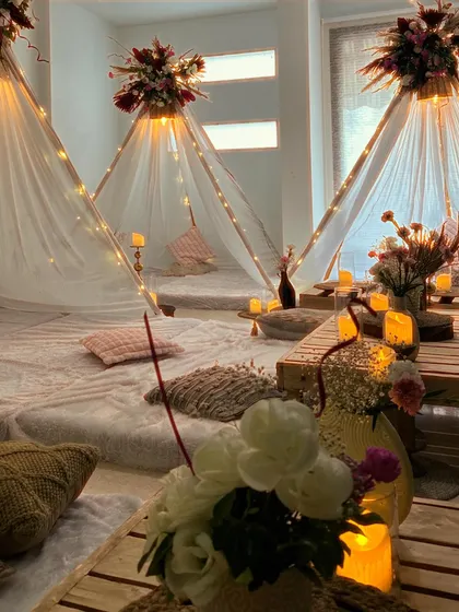 A wide shot of the dreamy slumber party setup, showing multiple teepees and the cozy, candlelit floor seating arrangement.