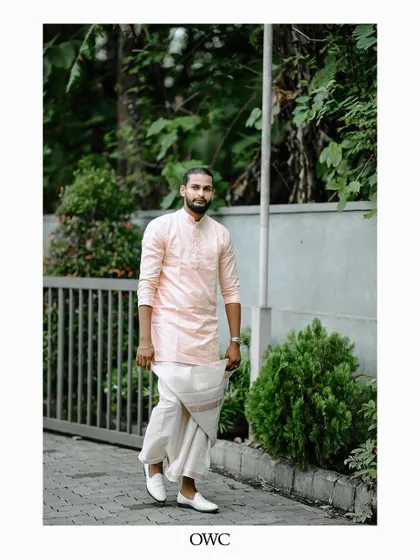 A full-length shot of the groom in his traditional mundu and kurta, looking stylish and ready for his wedding.