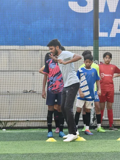 A coach demonstrating a drill to a group of young football players. My training sessions are hands-on, with coaches actively participating to ensure techniques are taught correctly.