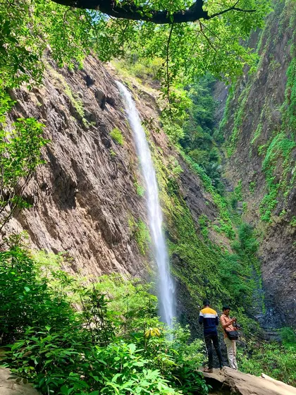 A promotional image for our Agumbe and Malpe New Year trip, featuring a majestic waterfall nestled in the jungle.