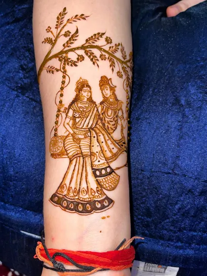 A serene portrait of Shiv and Parvati sitting on a swing under a tree. This design, placed on the forearm, is a beautiful expression of divine love.