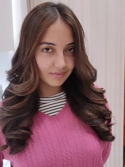 A happy client with beautiful, healthy-looking hair. The warm tones in her new color brighten her complexion and give her a radiant glow.