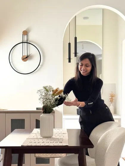 Setting up the cozy vibes in a dining corner. This behind-the-scenes shot shows me arranging flowers, adding the final elegant touch to the space.