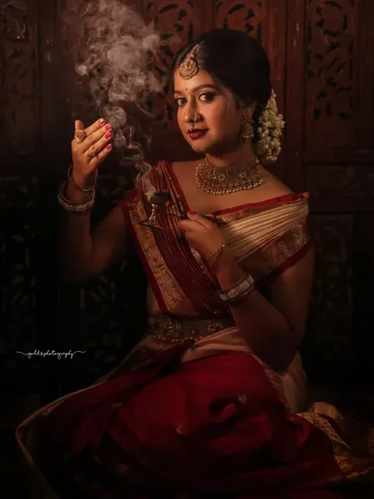 Portraits from a makeup shoot, showcasing a model in a classic red and cream saree. The images highlight the flawless makeup and traditional styling in a beautiful garden setting.