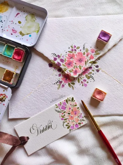 The process of creating one of the Guru Purnima tags, showing my watercolor palette and the delicate brushwork involved.