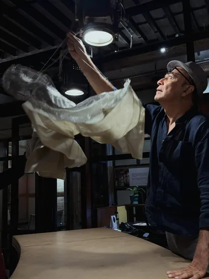 A candid shot of Puran Kumar adjusting a custom light fixture, a moment of focused expression at The Loft.