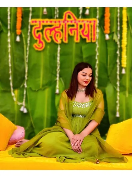 A serene portrait of a 'dulhania' at her Mehndi ceremony, seated against a vibrant, traditional backdrop of banana leaves and marigolds.