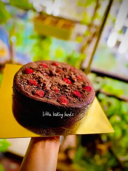 Holding up the chocolate strawberry cake to show its simple, rustic beauty before it heads out for a celebration. The natural colours of the fruit and cake are all the decoration it needs.