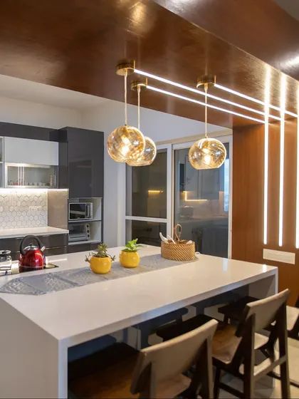 A closer look at the open kitchen for Mr. Verma. The combination of glossy grey cabinets, a white hexagonal backsplash, and warm pendant lights creates a modern and inviting atmosphere.
