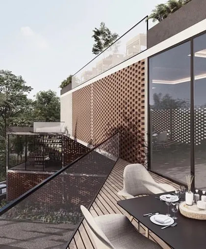 The restaurant terrace at the Kolgaon clubhouse. The space is designed as a glass box with an outdoor dining area, allowing for a seamless indoor-outdoor experience protected by a perforated brick screen.