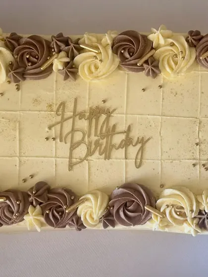 An elegant caramel sheet cake decorated with buttercream rosettes in chocolate and vanilla. I even pre-scored the top for easy, perfect portioning at the office party.
