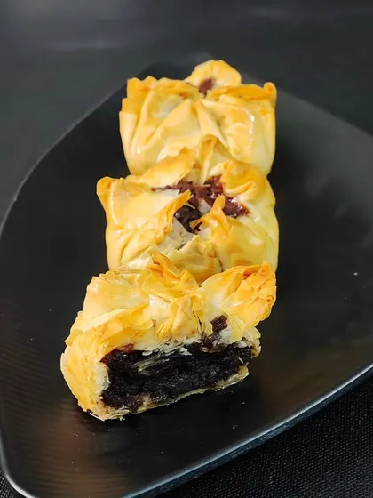A look inside the Baklava Brownie Bite. You can see the contrast between the crisp, layered pastry and the dense, chocolatey brownie center.