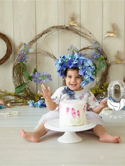 Pure delight. This is the moment after the first taste of cake, with a big, frosting-covered smile. The blue floral theme adds a soft, pretty touch to the celebration.