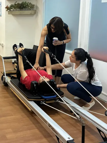 Hands-on learning is a critical part of our teacher training. Here, students practice cueing and correcting each other on the reformer.