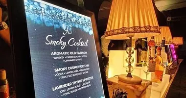 A close-up of our custom digital menu for a "Smoky Cocktail" station. We offer curated menus featuring drinks like the Aromatic Old Fashion and Smoky Cosmopolitan, complete with descriptions of their unique infusions.