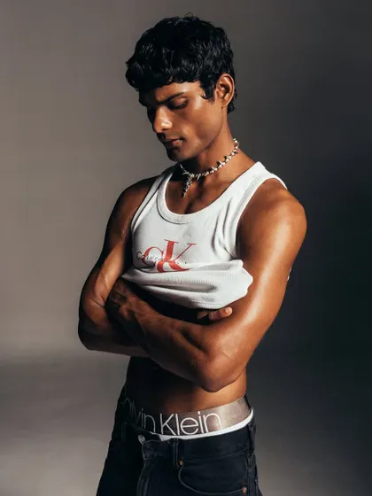 A quiet, introspective moment from the Calvin Klein shoot. The styling is minimal to emphasize the model's form and the classic appeal of the CK tank top, creating a timeless and authentic portrait.