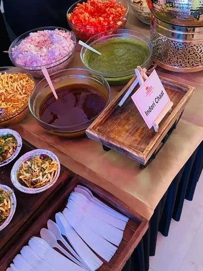 The complete setup for our Indori Chaat live station. All components, from the fried potatoes to the fresh chutneys, chopped onions, and sev, are neatly arranged for guests to customize their plate.