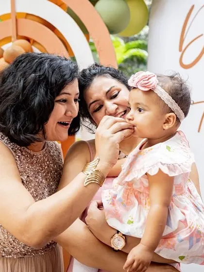 Candid moments from a first birthday party are just as important as the posed ones. Here, the birthday girl gets a loving bite of cake from a family member.